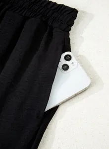 Close-up of side pocket on black wide-leg pants with a smartphone inside showing depth.