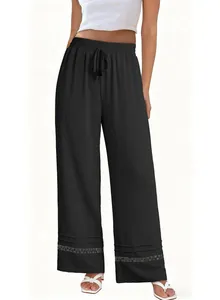 Detailed view of high-waisted black wide-leg trousers featuring a delicate lace hem