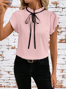 Close-up view of a pink short sleeve blouse featuring a ruffled collar and black bow tie.
