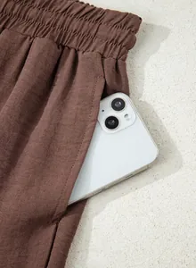 Detail shot of functional side pocket on brown linen-like casual high-waisted wide-leg pants