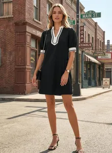 Full length view of a model wearing a black fashion vacation dress with white contrast trim