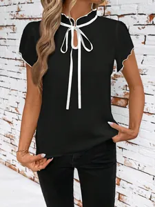 Detail showing a black short sleeve blouse with white ruffle trim and tie neck