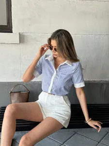 Women's blue and white striped colorblock polo shirt shown in a stylish outdoor setting