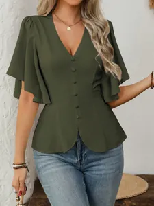 Dettaglio di una camicetta verde scuro con scollo a V, bottoni e vita a peplo elegante