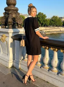 Model wearing a black straight dress with white collar in a Parisian street setting