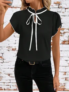 Close-up detail of women's black short sleeve blouse with white ruffle trim and a bow tie neck
