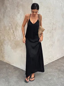 Detail of a black V-neck backless maxi dress worn by a model in a casual setting.