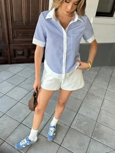 Outdoor view of a woman wearing a blue striped short-sleeve shirt with a contrast white collar.