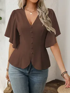 Dettaglio di un top marrone scuro con scollo a V e bottoni per un look molto chic