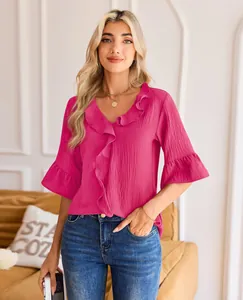 Close-up of pink V-neck blouse with elegant ruffle detailing on sleeves and neckline