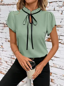Close-up of elegant light green blouse featuring ruffled collar and black bow tie detail