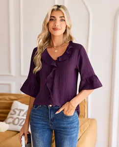A close-up view of a purple V-neck blouse with elegant ruffle trim and stylish bell sleeves