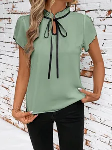 Detail of light green blouse featuring a ruffled collar and black bow tie ribbon