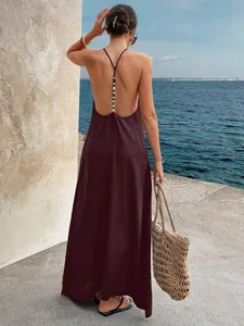 Back view of a burgundy backless maxi dress with beaded strap detail by the sea