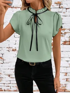Detail of light green short-sleeved blouse with black ribbon bow and ruffled collar