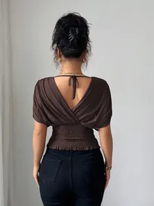 Detailed back view of a brown deep V-back top with smocked waist and tie detail.