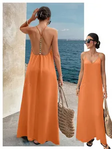 Detailed view of an orange backless maxi dress with beaded strap at the seaside.