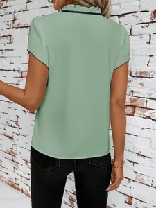 Back view of a sage green short-sleeved blouse featuring a ruffled collar and black trim.