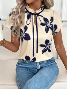 Detail of cream floral blouse featuring ruffled tie neck and navy flower print.