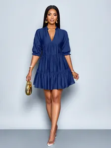 Detail view of a navy blue deep V-neck mini dress with puff sleeves and tiered pleats