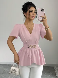 Elegante top a portafoglio rosa con pantaloni bianchi e accessori dorati da donna