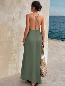 Back view of a sage green backless maxi dress with beaded strap detail at the seaside.