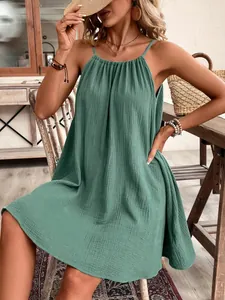 Détail d'une mini-robe verte sans manches ample avec une encolure licou plissée.