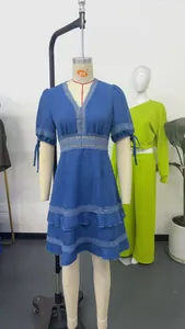 Dettaglio di un abito blu con scollo a V, inserti in pizzo e maniche a sbuffo