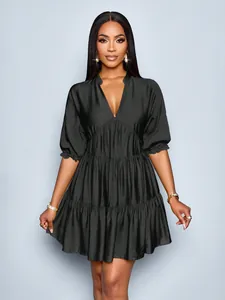 Detail view of a black puff sleeve mini dress with a deep V-neck and pleated tiers.