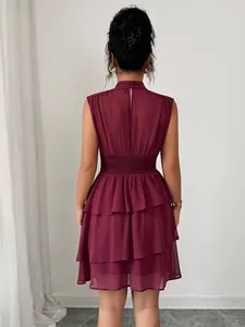 Vista posteriore dettagliata di un abito bordeaux senza maniche con balze e vita a nido d'ape