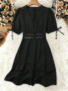 Elegante abito nero con scollo a V, inserti in pizzo e dettaglio traforato in vita