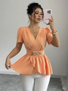 Dettaglio della camicetta peplum color pesca con scollo a V e cintura a catena dorata