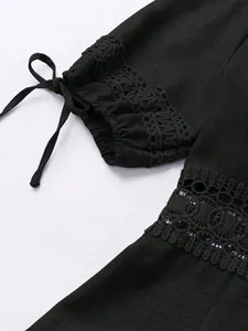 Dettaglio di un abito nero elegante con pizzo intricato e laccetto su manica a sbuffo