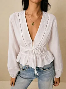 Detailed view of a white deep V-neck blouse featuring eyelet lace trim and cinched waist tie.
