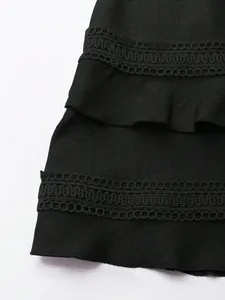 Dettaglio di abito nero con delicato pizzo traforato e orlo a balze decorativo