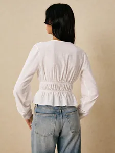 Back view of white long sleeve blouse with smocked waist and peplum hem detail.