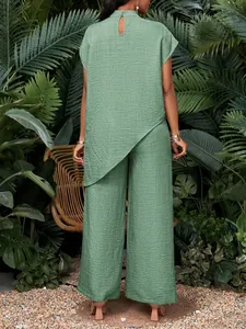Vista trasera de un conjunto verde con top asimétrico y pantalón de pierna ancha en jardín tropical.