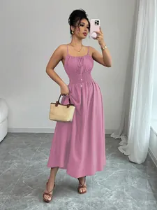 Full length view of a pink pleated waist cami dress on a model in a minimalist room.