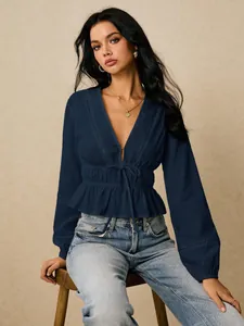 Detail view of a navy blue deep V-neck blouse featuring cinched waist and ruffle peplum hem