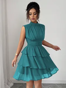 Dettaglio di un mini abito a balze senza maniche con collo alto in chiffon verde