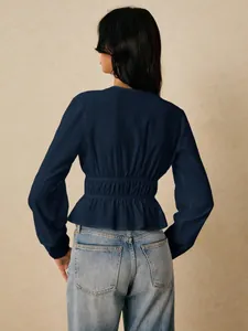 Rear view of navy blue peplum blouse showing elastic cinched waist and lace cuff details