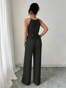 Πίσω όψη κομψής μαύρης ολόσωμης φόρμας halter με φαρδύ παντελόνι και δέσιμο στη μέση.