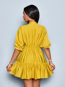 Back view of a mustard yellow pleated mini dress with puff sleeves and ruffled hem.