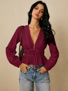 Detailed view of the deep V-neck, tie-waist, and hollow-out lace on the burgundy blouse