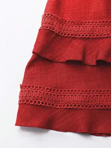 Dettaglio dell'orlo del vestito rosso a balze con pizzo delicato e trama in tessuto