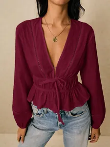 Close-up of maroon deep V-neck blouse with hollow-out lace and ruffled hem.