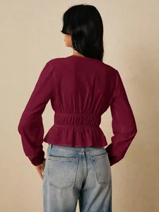 Detailed back view of a burgundy long sleeve smocked waist blouse with a ruffle hem