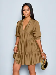 Detailed view of bronze deep V-neck mini dress featuring tiered pleated skirt and puff sleeves