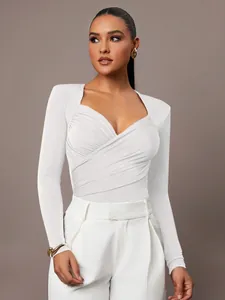 Dettaglio di body bianco a maniche lunghe con elegante scollo a V incrociato e ruches