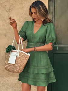 Dettaglio dell'abito verde con scollo a V, inserti in pizzo e maniche a sbuffo